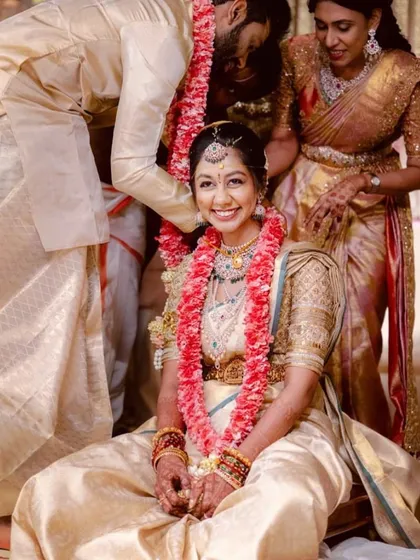 The bride's smile says it all. Her custom-designed cream and gold silk saree outfit, featuring a blouse with subtle gold embroidery, was perfect for her traditional wedding ceremony.