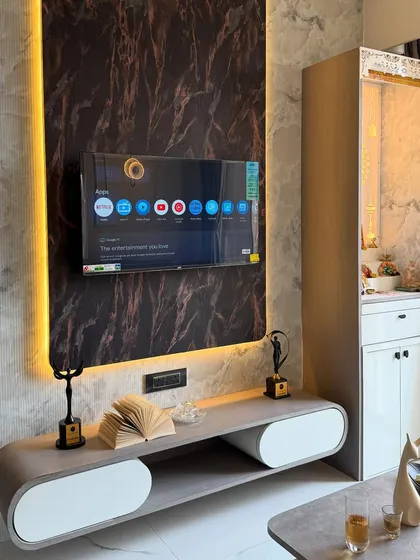 A slightly different angle of the TV and pooja unit combination, showcasing the sleek, modern console table with curved edges and minimalist decor.