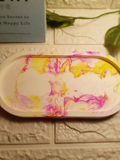 Our oval trinket tray with a vibrant pink and yellow marble pattern that reminds us of candy.