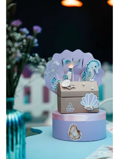 A charming, custom-made favor box with a seahorse and mermaid tail motif. The party favors are always designed to be a beautiful and thematic keepsake from the celebration.