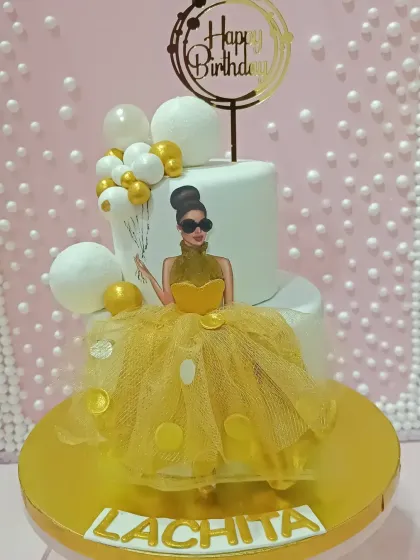 A chic and fashionable two-tiered cake. This design features a stylish illustration of a woman in a yellow gown, with the fabric of the dress made from real tulle.