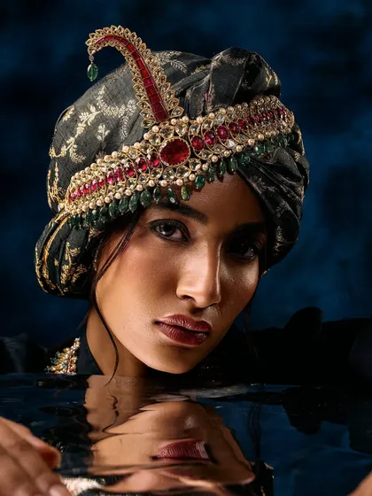 This creative shot for a men's jewellery campaign uses water to add a unique reflective element. The focus remains sharp on the ornate turban accessory, with its rich red and green stones, creating a moody and unforgettable image.