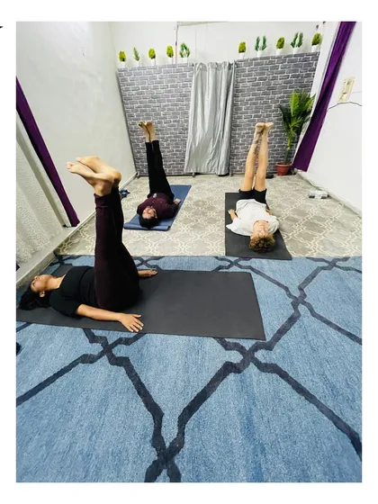 A small group class working on leg raises to build core and lower body strength. The focus is on controlled movement and breath synchronization.