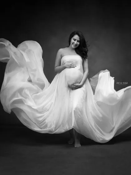 A full-body shot showcasing the magic of flowing fabric. In black and white, the texture and movement of the gown become the central focus of this artistic portrait.
