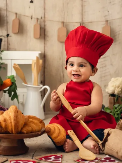 A happy baby chef surrounded by props in a rustic kitchen setup. This is a great idea for a unique sitter session.