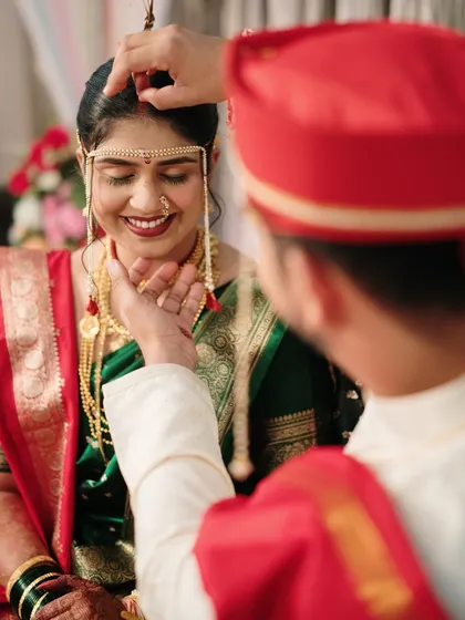 The groom applies the sindoor, a deeply significant moment in a Hindu wedding. We capture this ritual with a close-up, focusing on the bride's blissful expression and the tenderness of the act.