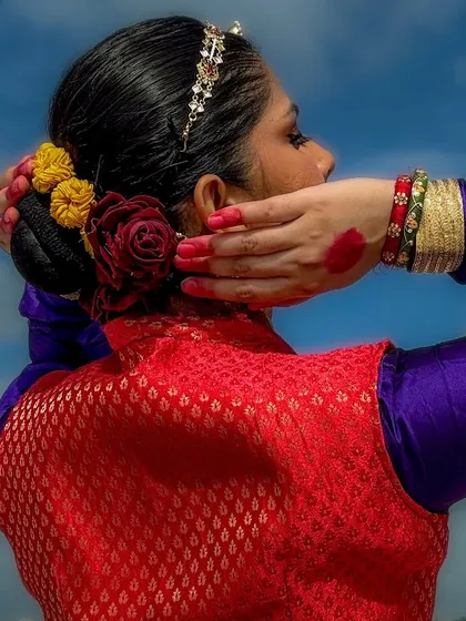A celebration of womanhood. This back profile highlights the traditional hairstyle adorned with flowers, a classic element of a dancer's adornment.