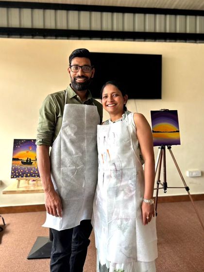 A couple stands proudly together after completing their paintings. The sense of shared accomplishment is one of the best parts of our workshops.