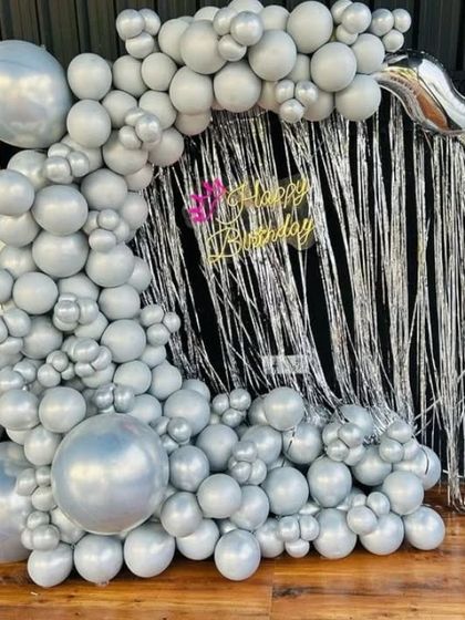 A modern and chic all-silver balloon decoration. This setup features an organic balloon arch over a silver tinsel backdrop, creating a sleek and glamorous photo corner.