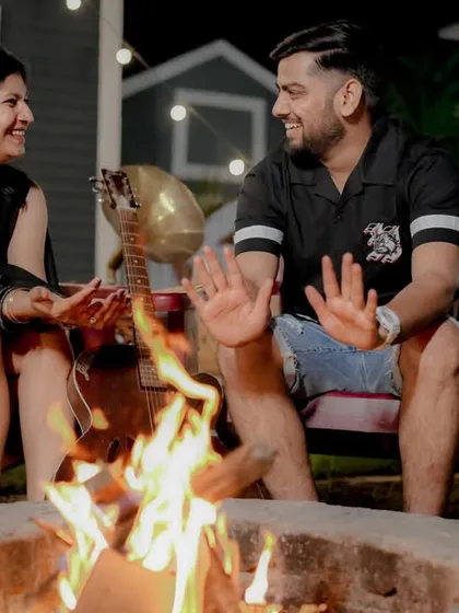 Cozying up by the bonfire for an evening pre-wedding shoot. The warm glow of the fire and the string lights create a magical and intimate atmosphere, perfect for romantic and relaxed photos.