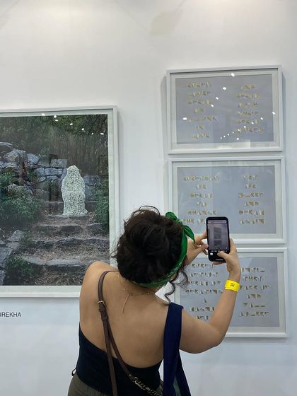 A visitor taking a close-up photo of Surekha's work, highlighting the intricate details.