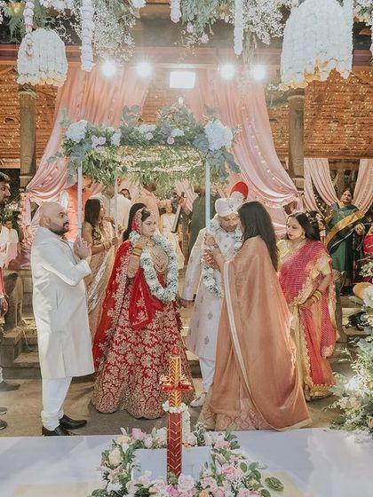 A wide shot of the wedding ceremony, showing the beautiful floral mandap and guest seating.