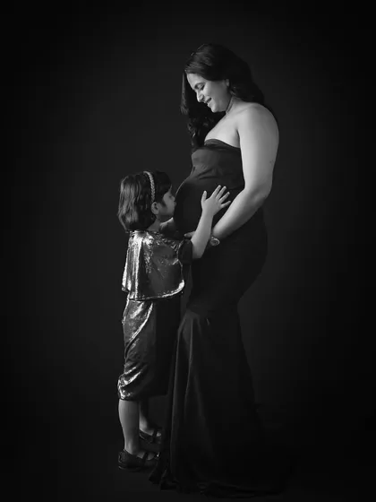 A simple, powerful black and white maternity portrait. This image focuses purely on the beautiful bond between a mother and her daughter as they anticipate the arrival of a new family member.