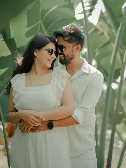 A playful and loving embrace amidst lush greenery. The couple's sunglasses and bright smiles give this candid shot a fun, relaxed vibe, perfect for a sunny day shoot in Pune.