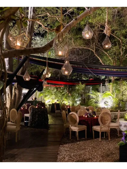 An enchanting evening setup at the Garden of Five Senses, with hanging lanterns and elegantly set tables. This showcases the magical ambiance our team helps create in collaboration with top decor vendors.