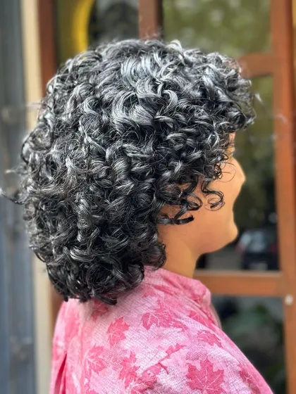 Showcasing the beauty of natural silver curls with a chic short haircut. This style is all about embracing texture and creating a sophisticated shape.