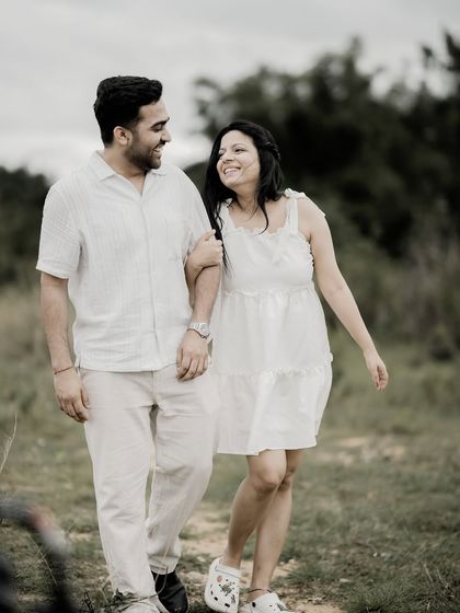 A happy, candid shot of a couple walking arm-in-arm through a field, sharing a smile.