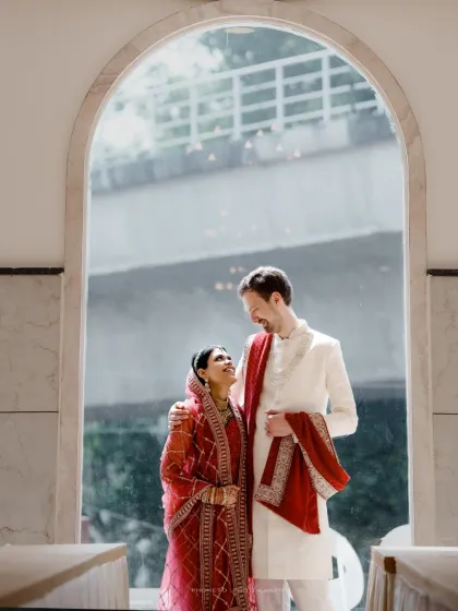 A joyful and bright portrait of the Nikah couple, framed by an archway, capturing their happiness in natural light.