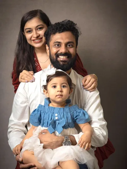 A sweet family portrait with the parents framing their little one. This pose creates a sense of love and protection, highlighting the child at the center.