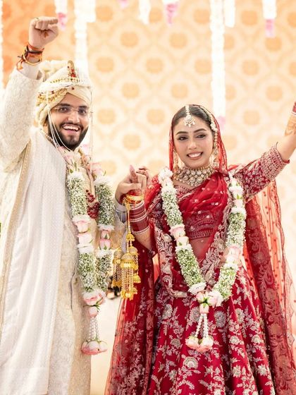 A moment of pure celebration. The couple raises their hands in joy after the varmala ceremony, marking the official union.