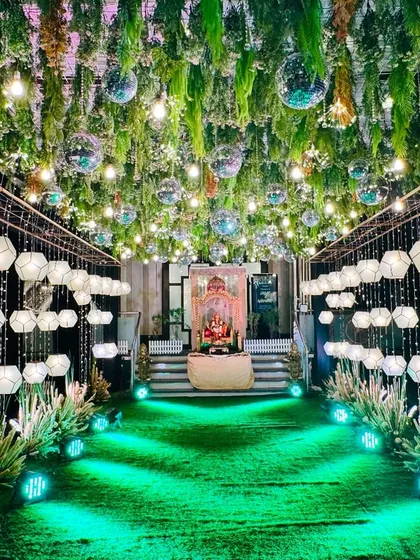 I created this spectacular walkway for a Sangeet by hanging hundreds of geometric lanterns and disco balls from a ceiling of lush greenery. The green uplighting on the path adds to the dramatic, party-ready feel.