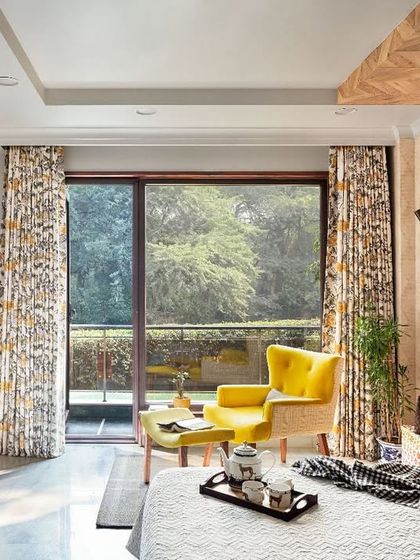 The bedroom at Ridge View is personal and expressive. A neutral canvas allows vibrant elements like the canary yellow accent chair to take center stage, while a herringbone wooden panel on the ceiling adds a touch of drama.