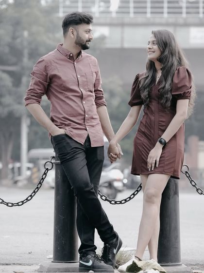 A classic romantic pose, holding hands and looking at each other, set against a casual city street backdrop.