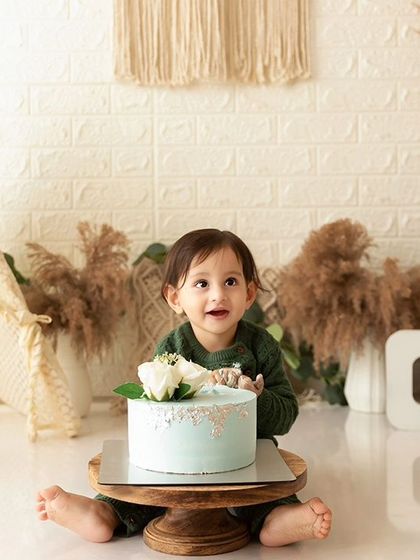 The birthday boy posing with his cake before the smashing begins, set against a stylish boho teepee backdrop.