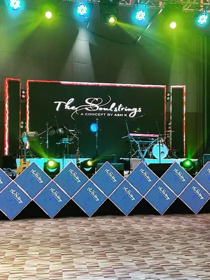 The stage setup for the live band, "The Soulstrings," at a Roka ceremony, featuring a large LED screen and custom-branded speaker covers.