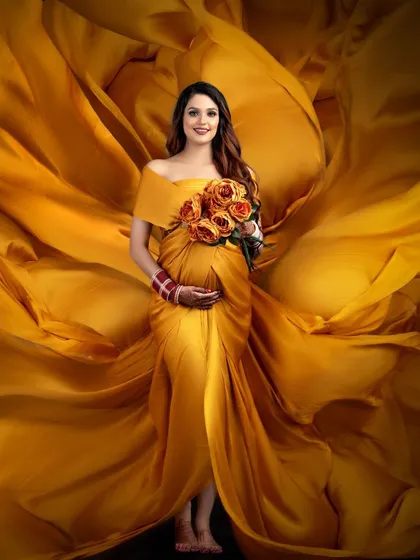 A stunning portrait where the client is enveloped in a swirl of golden-yellow fabric. This artistic technique creates a beautiful, flower-like effect for a truly unique maternity photo.