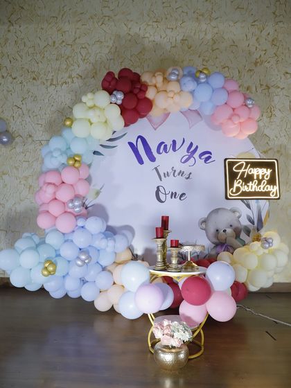 A beautiful pastel rainbow balloon backdrop for Navya's first birthday cake-cutting ceremony.