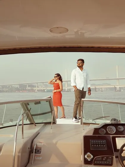 A wide shot from inside the yacht, framing the couple against the open water. This perspective gives a sense of the luxury and privacy of a yacht photoshoot.