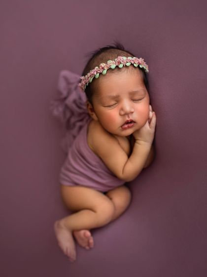 A simple and sweet beanbag pose in a lovely purple wrap. This pose is all about comfort and showing off the baby's peaceful expression.