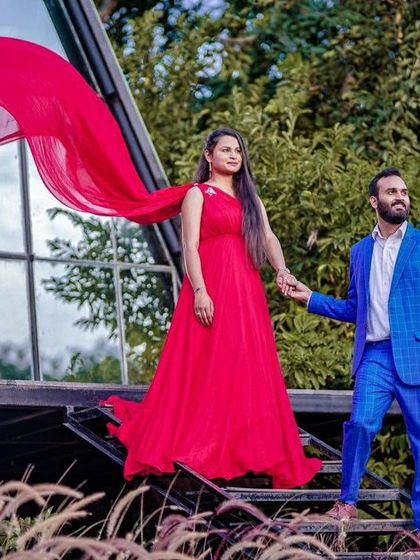 This couple's pre-wedding photo has a dramatic, adventurous feel. The red flying gown and blue suit create a powerful color combination against the natural landscape.