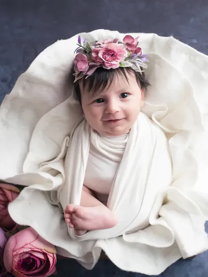 A beautiful newborn girl, wide-eyed and curious, nestled in a floral prop. I love capturing those rare moments when newborns are awake and calm, showing their budding personality right from the start.