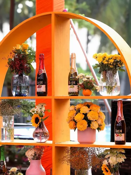 Another view of the orange arched shelving, showcasing a mix of florals and beverages, adding both function and style to the event.