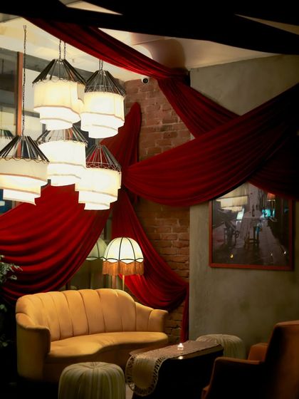 A lounge area at Gigi, with dramatic red draping and elegant lighting, creating a sophisticated and festive atmosphere.