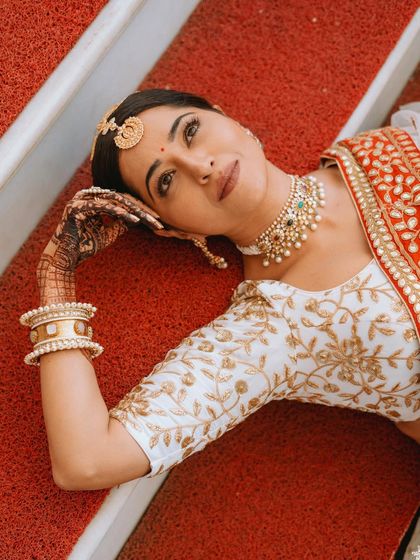 A thoughtful and artistic portrait of the bride, her hand gently resting on her head, showcasing her intricate mehendi.