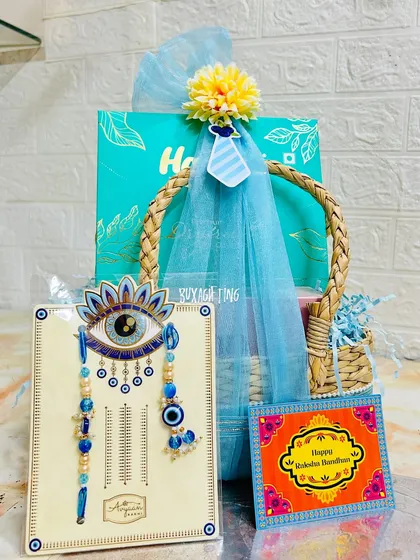 The evil eye rakhi set is the star of this Bhai-Bhabhi hamper, complemented by a box of dry fruits and a festive greeting card.