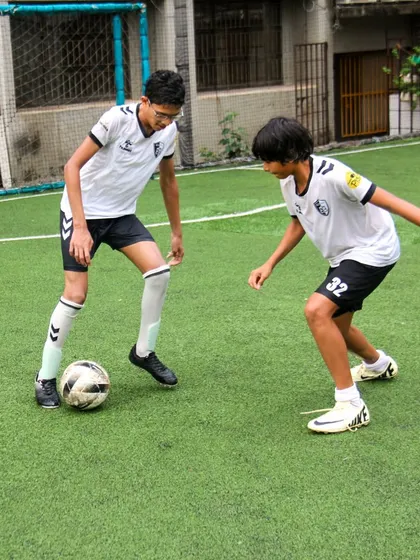 A player uses his body to shield the ball from an opponent, demonstrating smart and physical play to maintain possession.