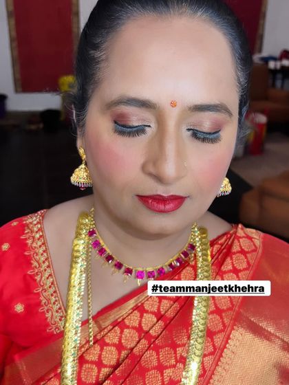 A close-up of the mother of the bride's makeup, showing the soft shimmer on the eyes and the perfectly applied red lipstick.