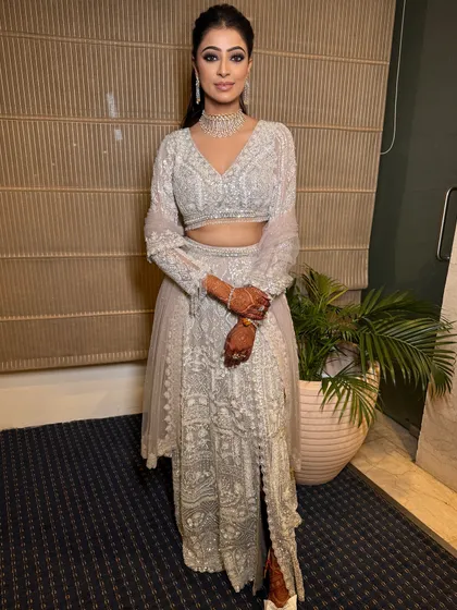 The full look for this modern engagement ceremony. The high-slit lehenga and sleek ponytail are perfectly complemented by the bold, glamorous makeup.