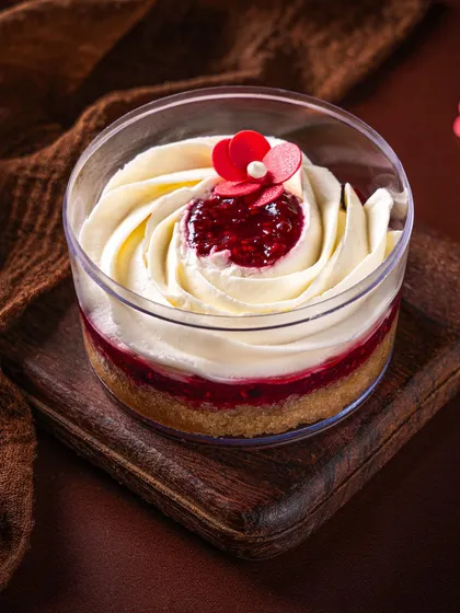 Our Vanilla Berry dessert tub, with layers of vanilla cream, berry compote, and a biscuit base. It's a light and fruity dessert, beautifully presented with a swirl of cream and a delicate sugar flower.