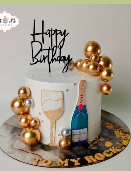Pop the bubbly! A chic and celebratory birthday cake featuring a Moët bottle, a champagne glass, and a cascade of gold and silver spheres.