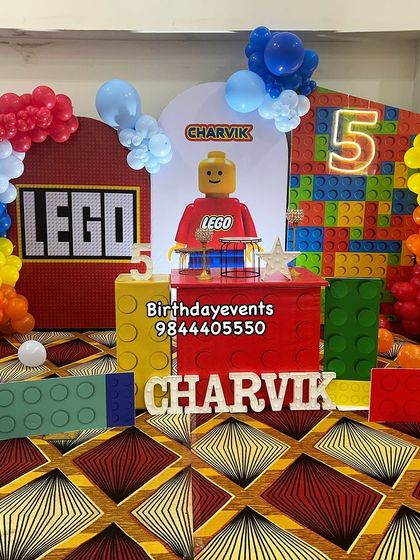 Everything is awesome with this Lego-themed 5th birthday party. The decor features a giant Lego block backdrop, a Lego character, and colorful balloon clusters.