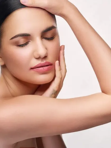 A beauty shot showcasing flawless skin and a relaxed, natural expression. The clean, high-key lighting on a white background is a standard for commercial beauty photography.