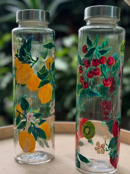 A set of upcycled glass bottles painted with lemon and cherry designs, turning simple kitchen items into art.