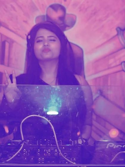 A stylized shot from behind the decks, capturing the cool, purple-lit vibe of the club.