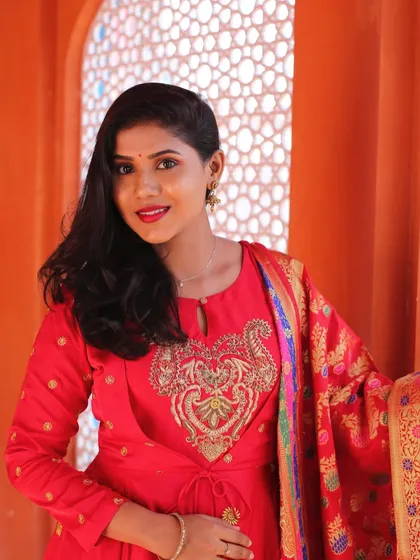 A vibrant look for a pre-wedding photoshoot. The red outfit and bold lip stand out beautifully against the colorful backdrop.