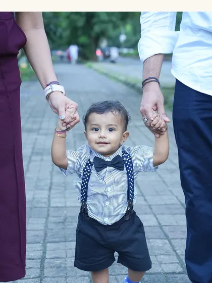 A baby's first steps are a memory a family holds forever. Here, little Krishiv is safely guided by his parents' hands, a simple, powerful image of love and support that defines family photography.